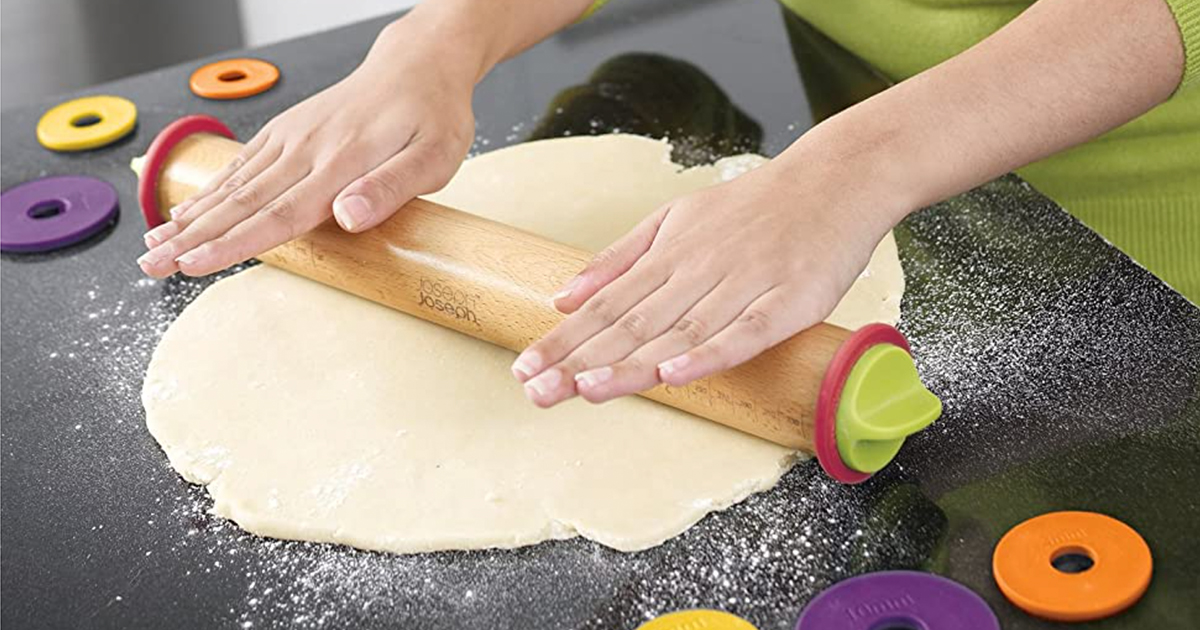 hands using a joseph joseph rolling pin to roll out dough on a floured counter