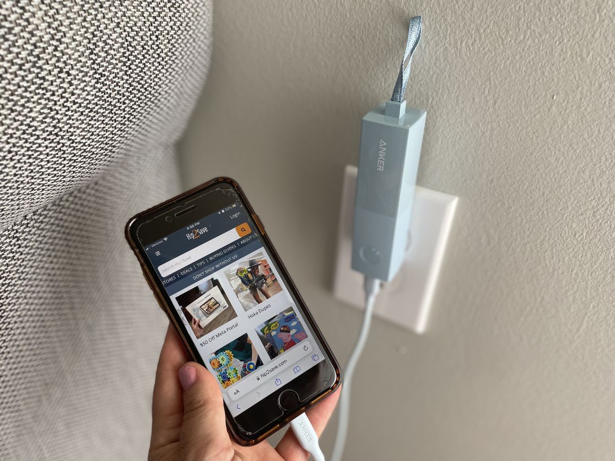 hand holding phone connected to power bank plugged into the wall