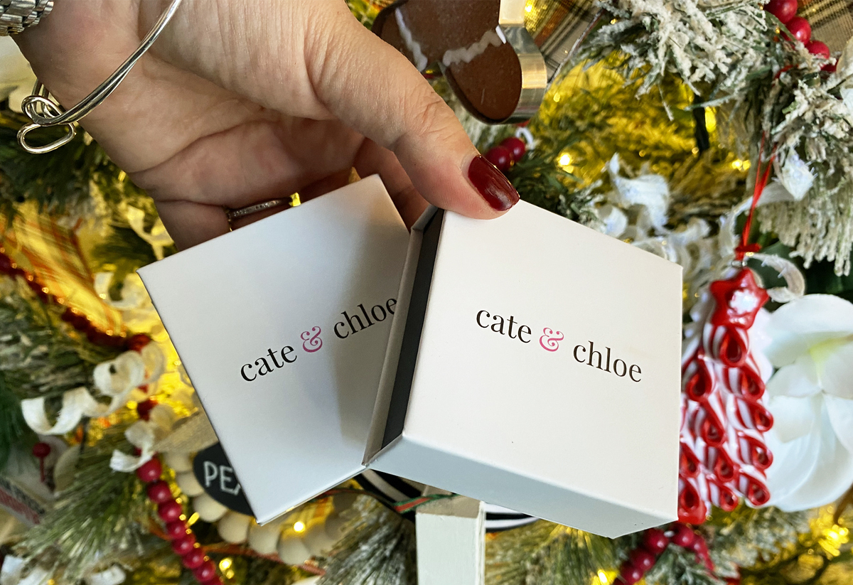 hand holding cate & chloe gift boxes near christmas tree