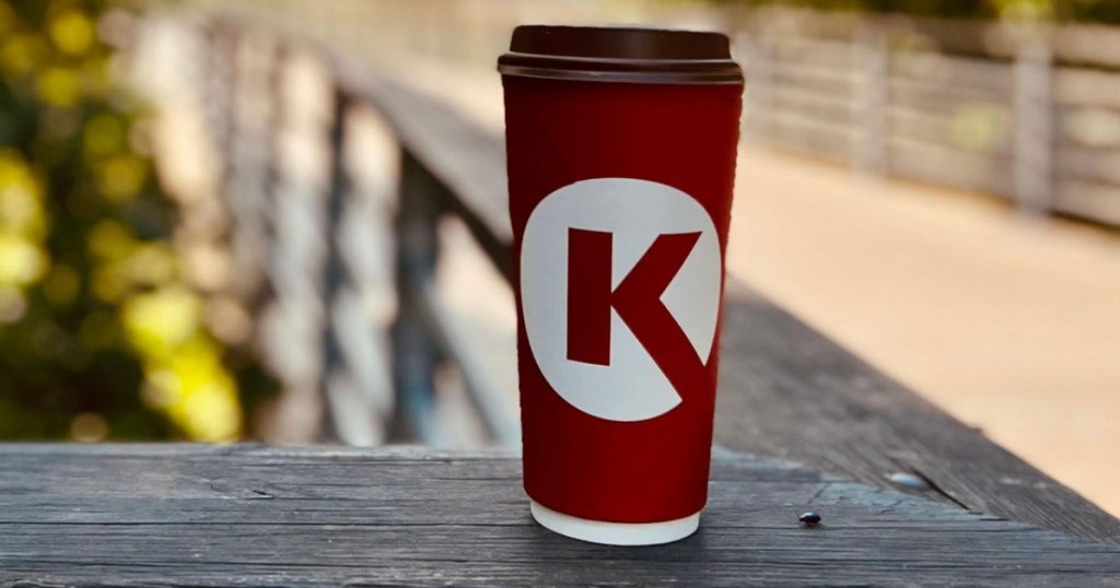 Circle K coffee with lid sitting on top of wood railing outside