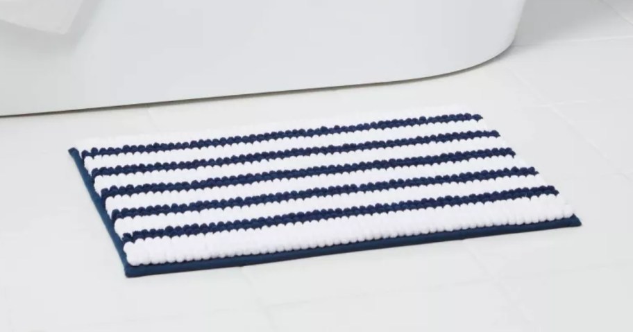 a blue and white striped bath mat on a white tile floor