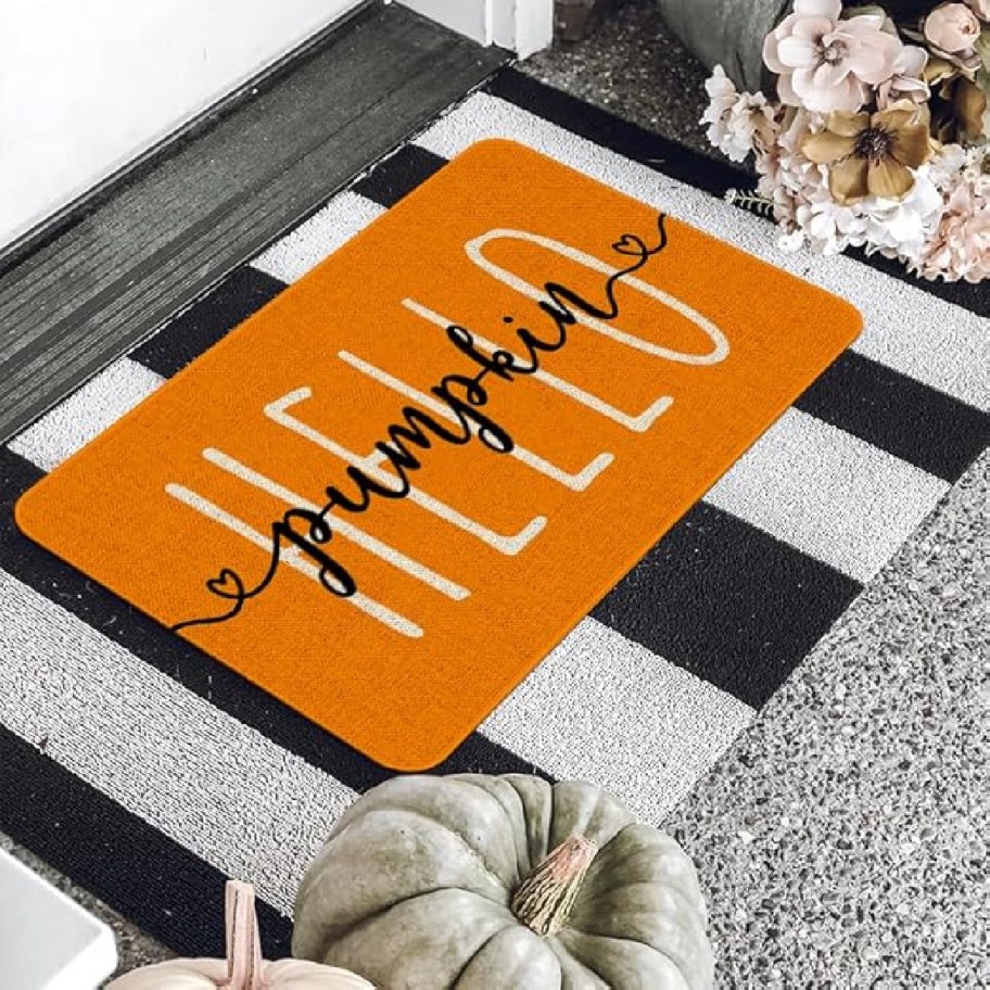 Hello Pumpkin Halloween Doormat from Amazon on a front porch surrounded by pumpkins