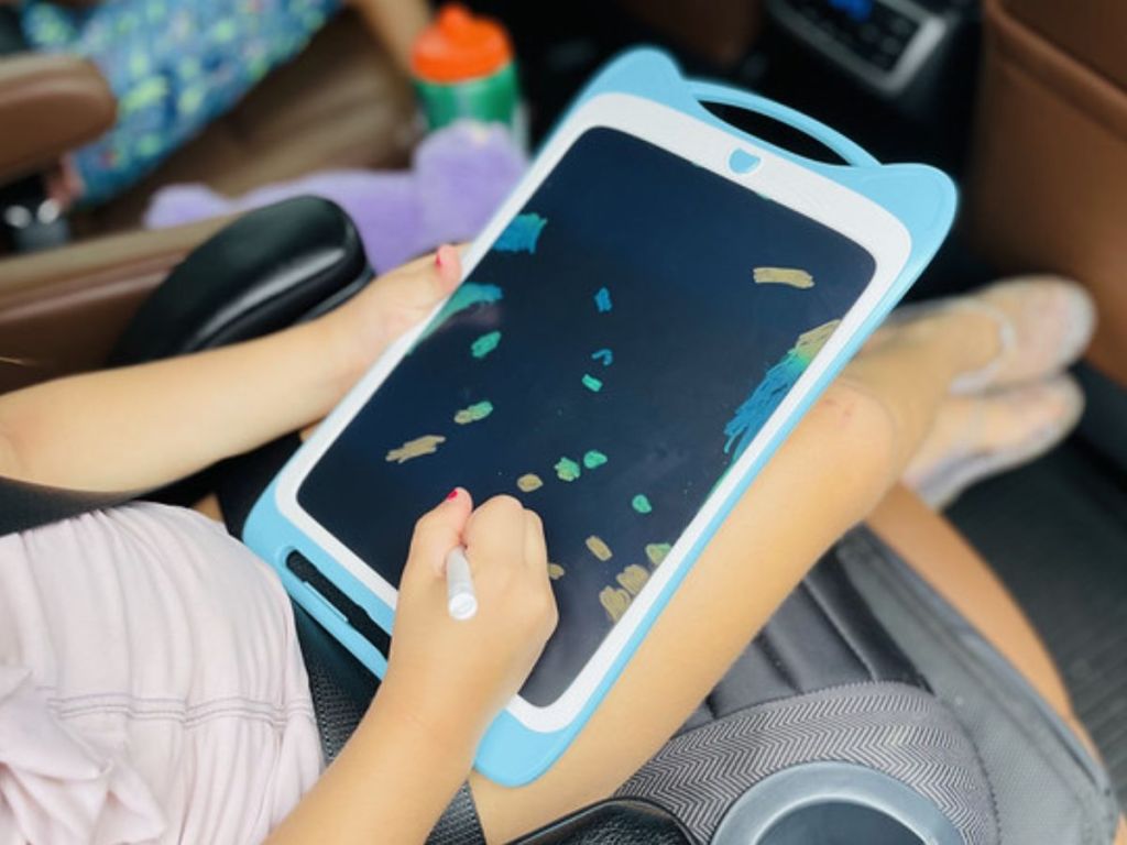 Little girl drawing on a Jasonwell 10" Kids Drawing Doodle Boards in the car