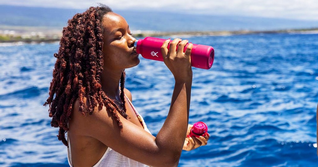 woman drinking from pink hydro flask bottle