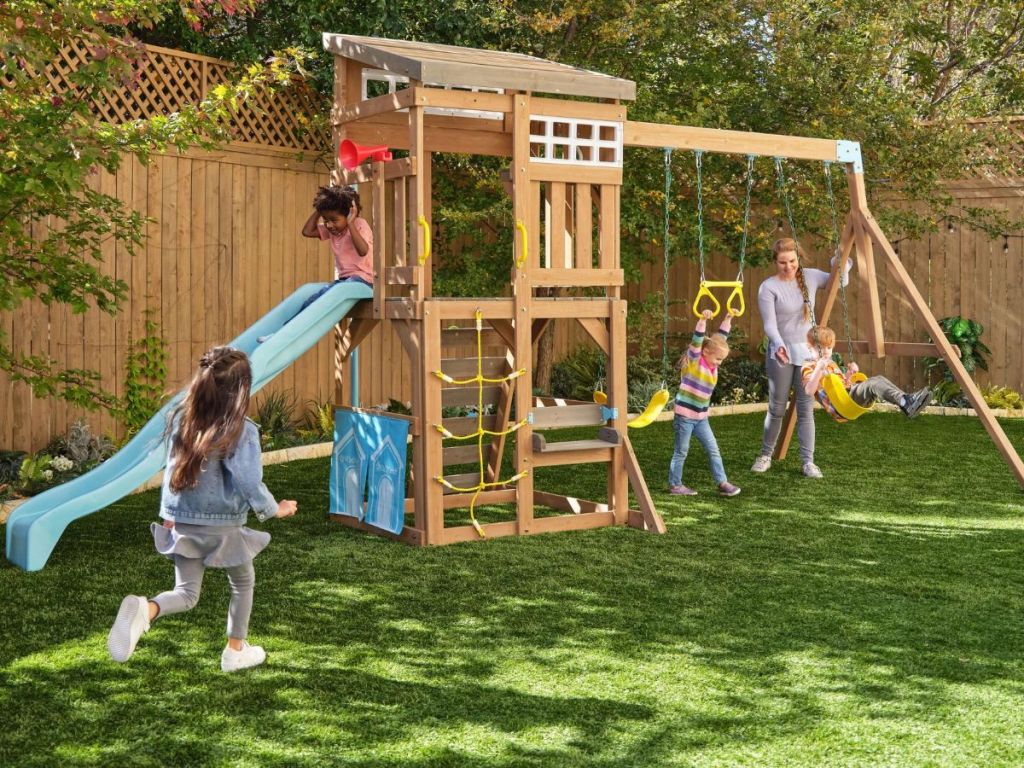 A kidkraft swingset with kids playing on it