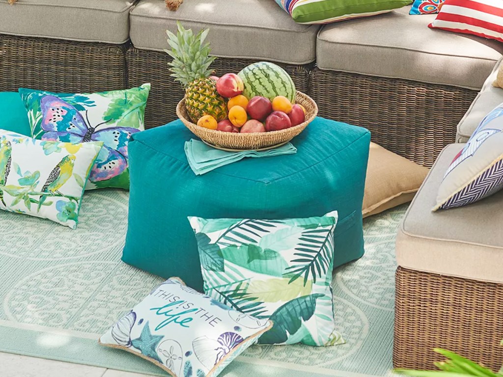 teal ottoman pouf surrounded by throw pillows near outdoor couch