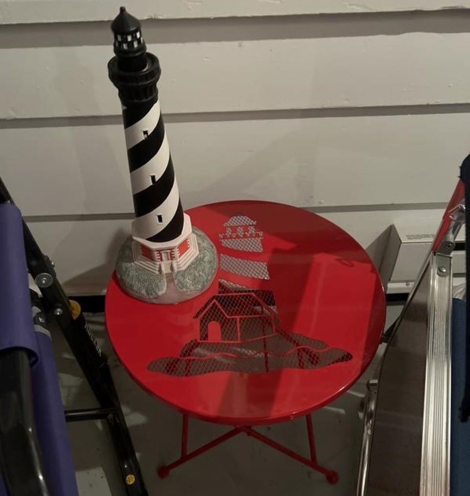 Patio table with a lighthouse statue on it and a lighthouse design on the table