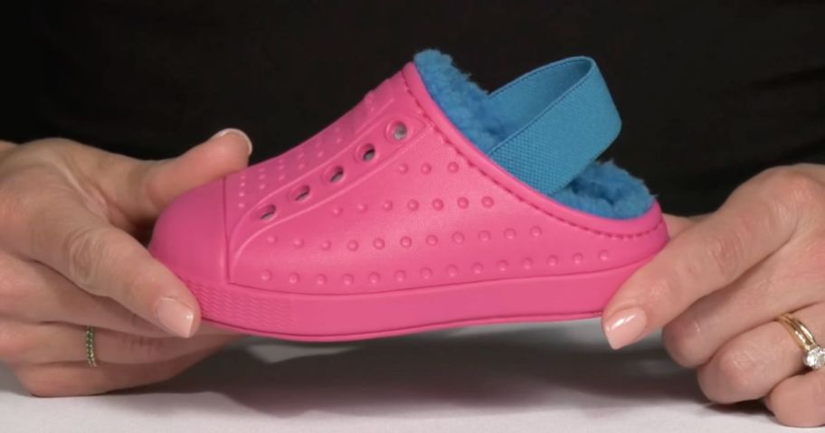 A woman holding a pink and blue Native Toddler Shoe