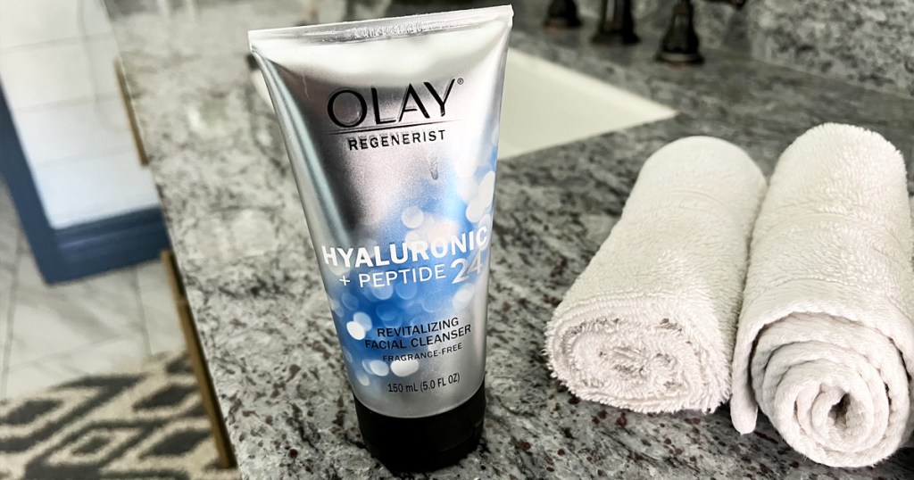 olay cleanser on bathroom counter with rolled towels