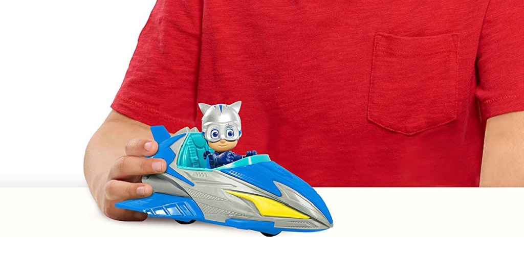 boy in a red shirt playing with a pj masks vehicle toy
