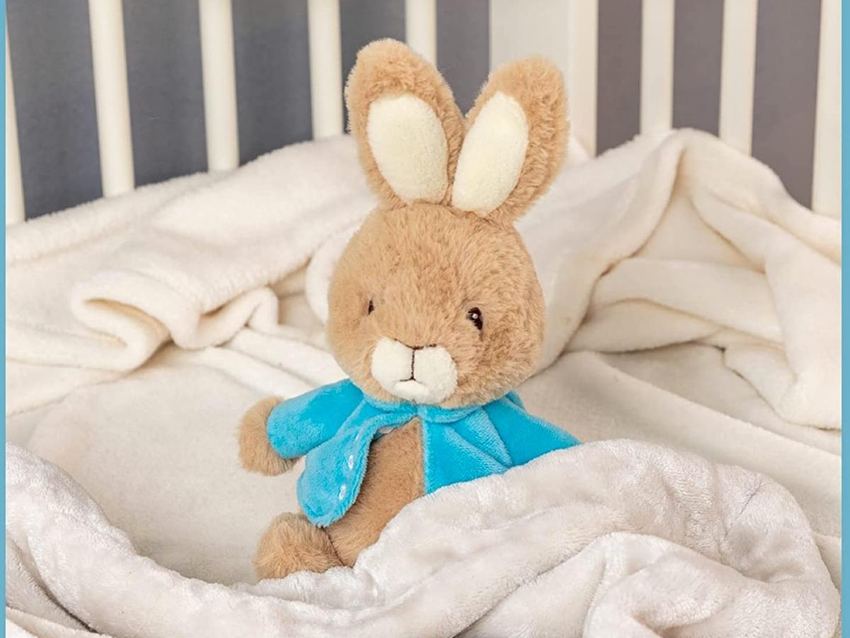 Peter Rabbit Plush Bunny nestled in blankets in a crib