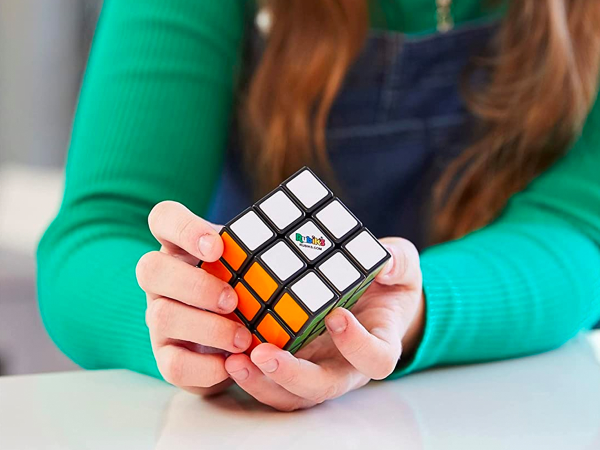 close up of a girl wearing a green shirt and playing with a Rubik's Cube