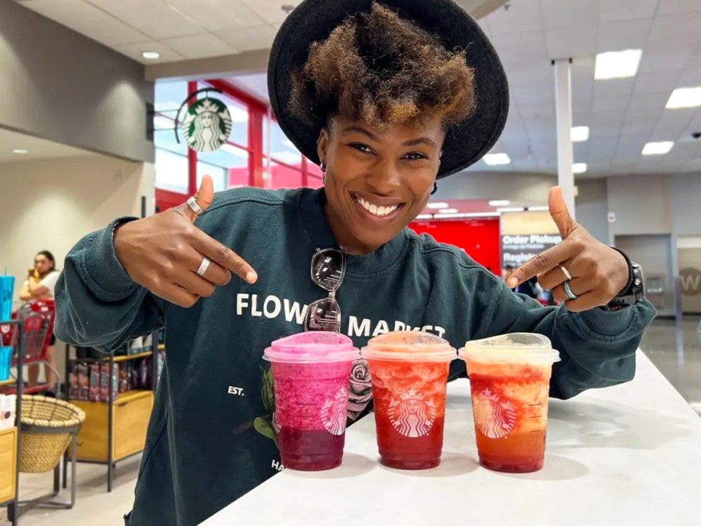 Frau zeigt auf drei Starbucks Frozen Lemonades