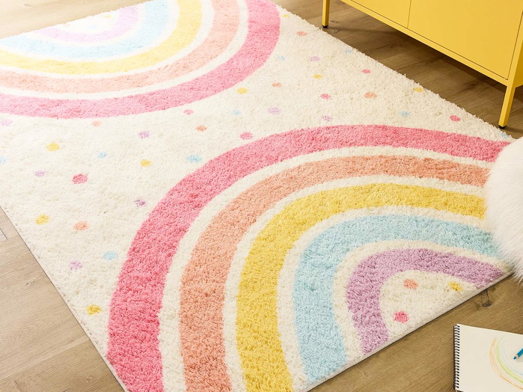 pink, orange, yellow, blue, and purple rainbow area rug on wood floor