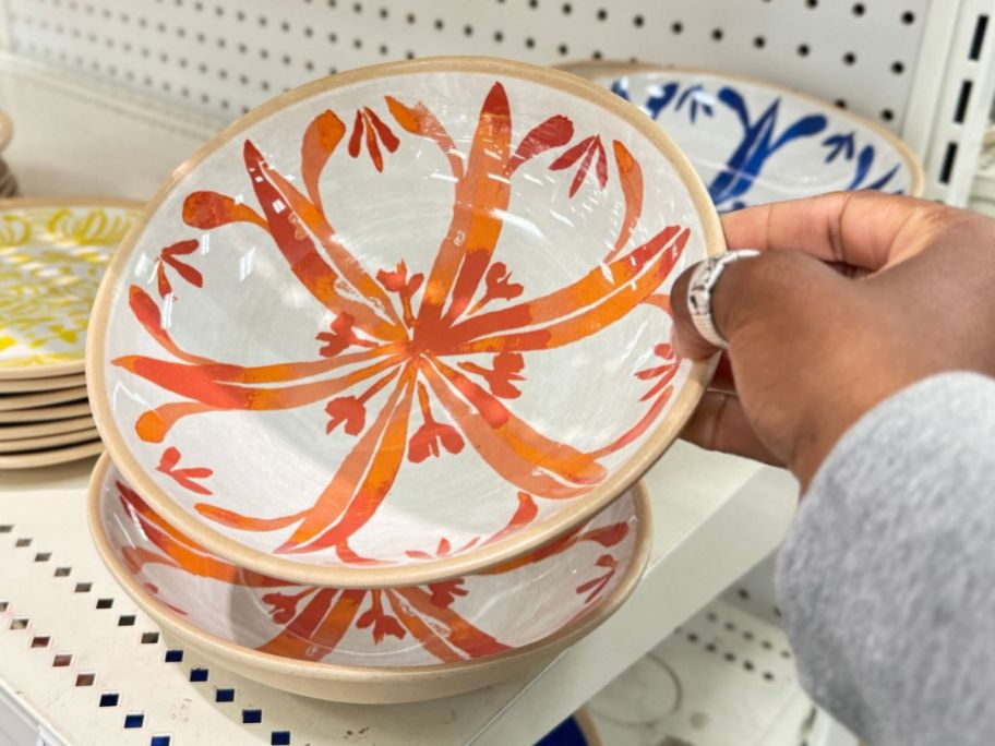 Hand pickingup a Threshold cereal bowl from a shelf full of them at Target