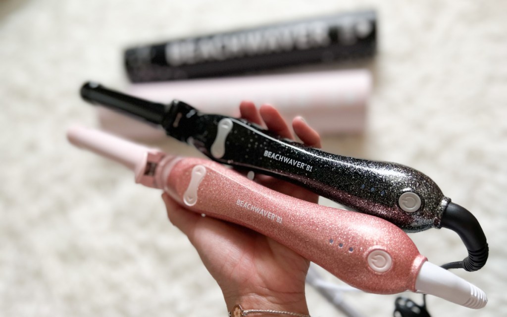 hand holding pink and black glitter curling wands