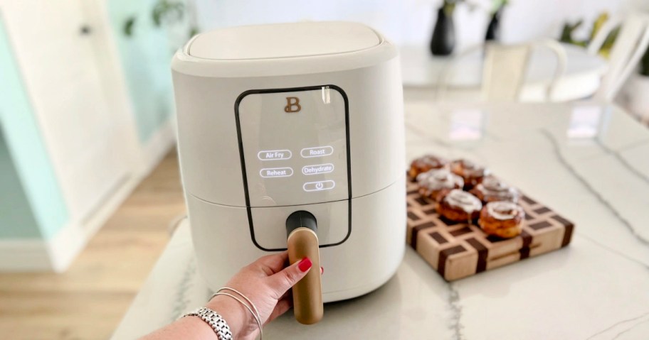 hand grabbing handle on white drew barrymore air fryer