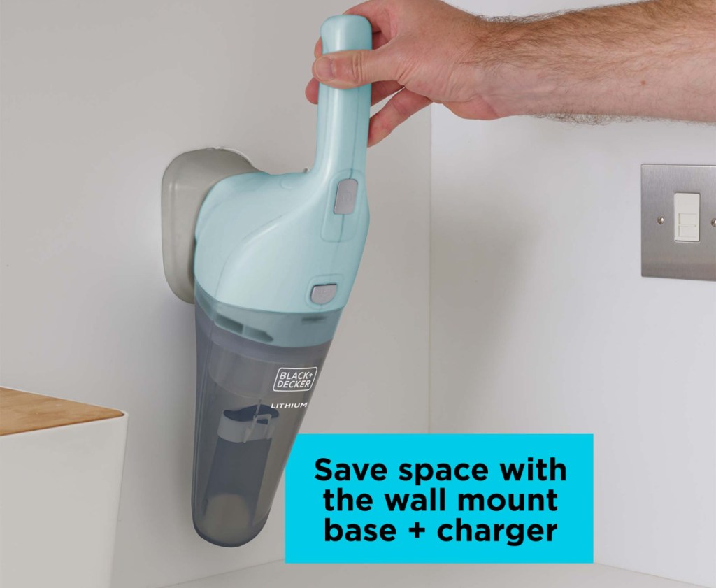 cordless black and decker handheld vacuum mounted on a wall with a hand holding the handle