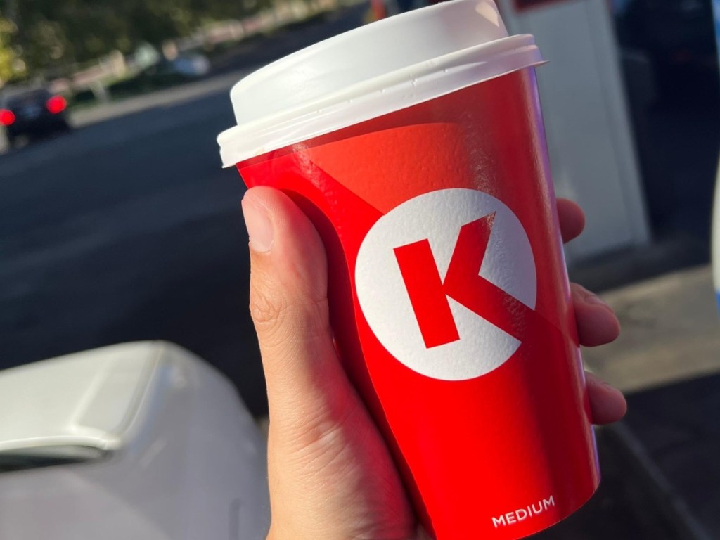 holding a Circkle K coffee cup