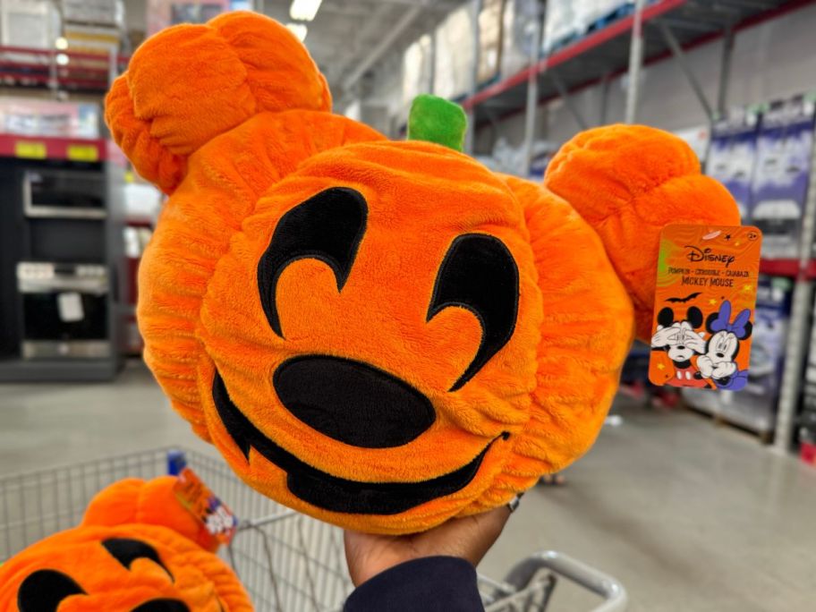 a womans hand displaying a mickey mouse pumpkin plush