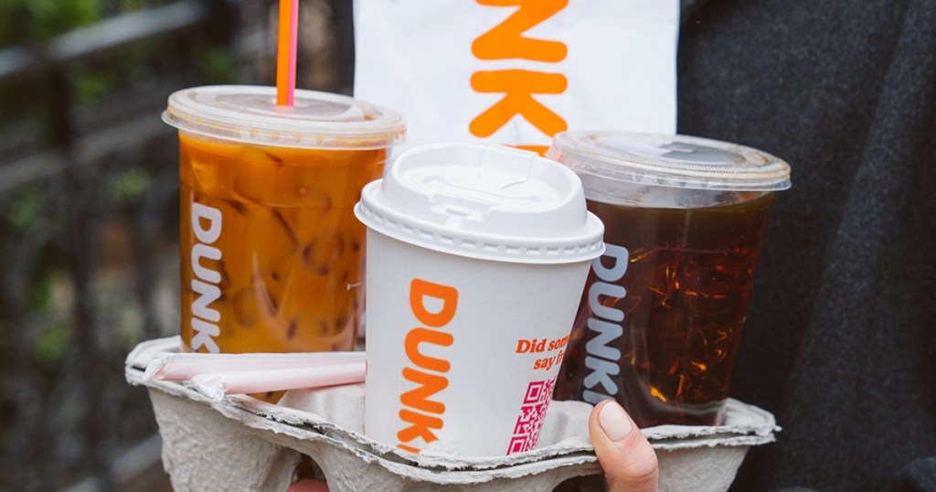 holding a tray filled with 3 Dunkin coffee drinks and a bag