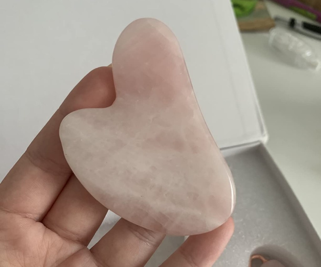 hand holding rose quartz gua sha