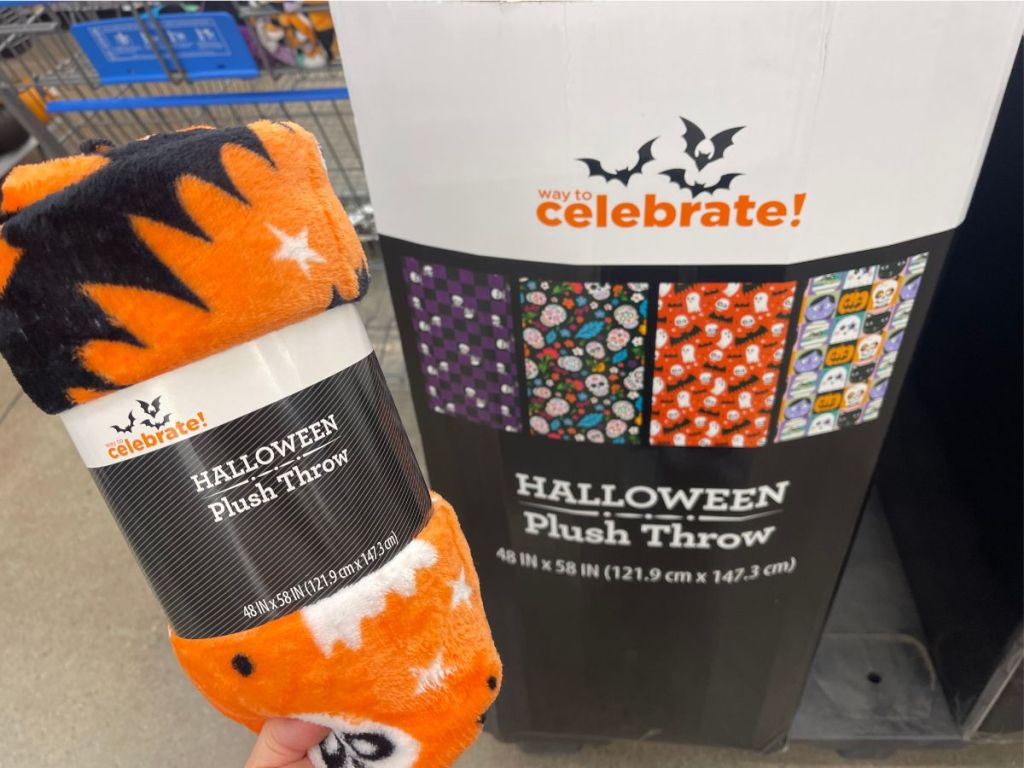 hand hodling Halloween plush throw in store in front of display