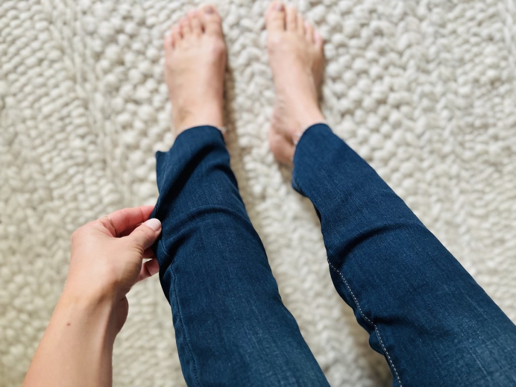 hand pulling at extra fabric on jeans