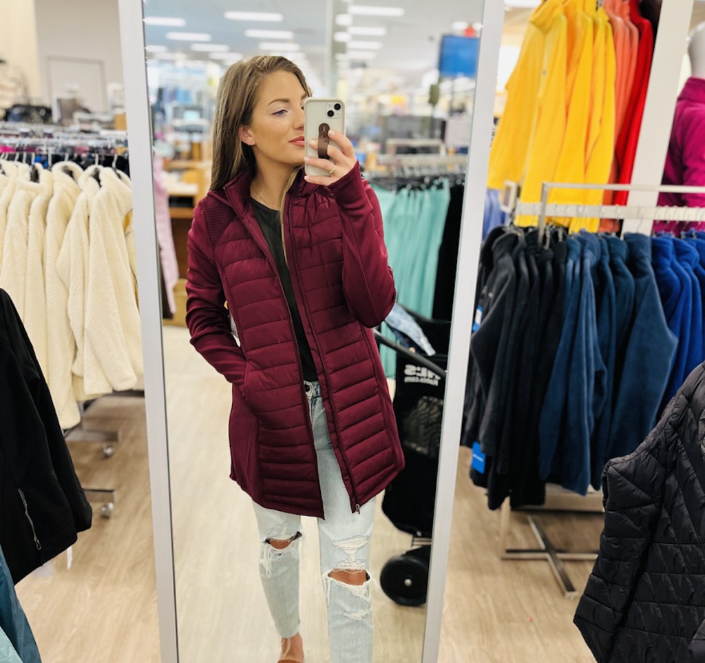 woman taking mirror selfie at kohls with red quilted jacket on