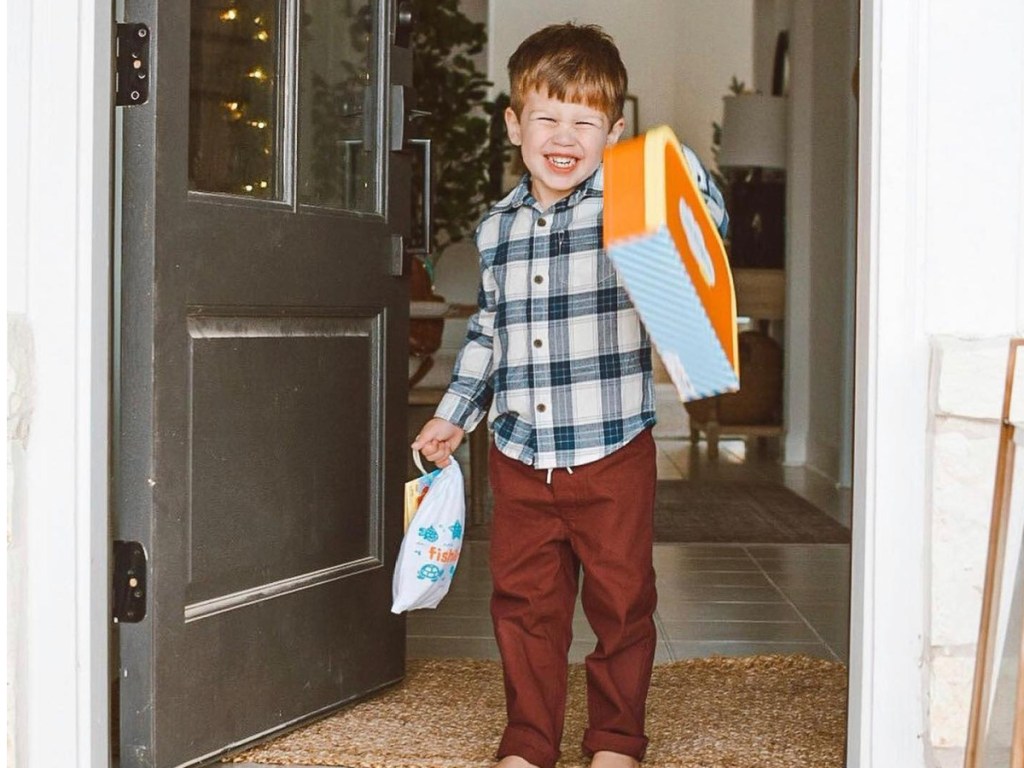 boy holding little pasports box in door
