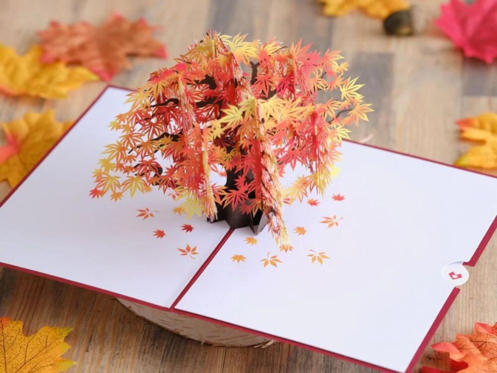 maple tree card on wood table surrounded by maple leaves