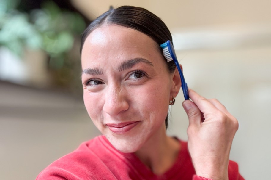 woman brushing side hair down with toothbrush