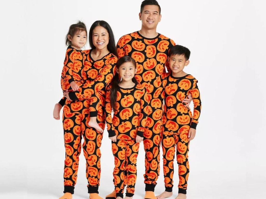 family wearing matching pumpkin pjs