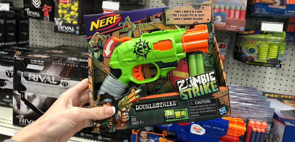 hand holding a nerf zombie blaster in front of a store display wall
