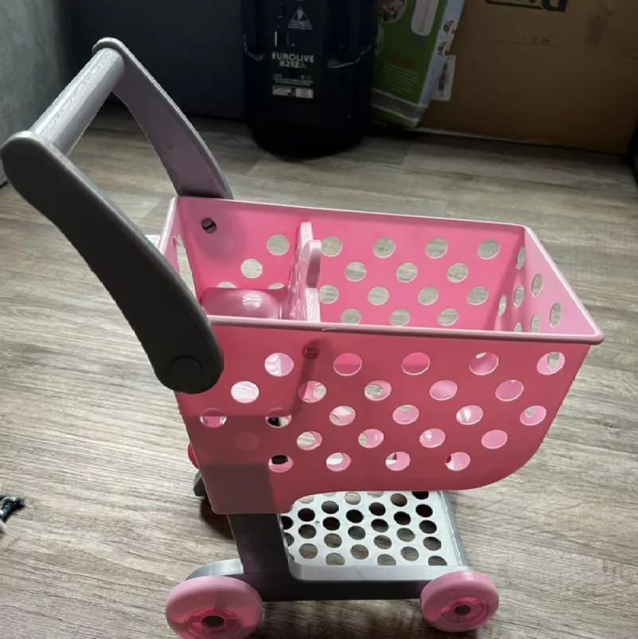 perfectly cute toy shopping cart in pink sitting in the middle of a floor