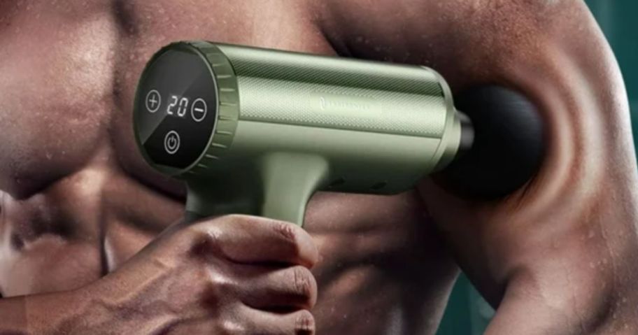 a man's hand holding a massage gun to his bicep