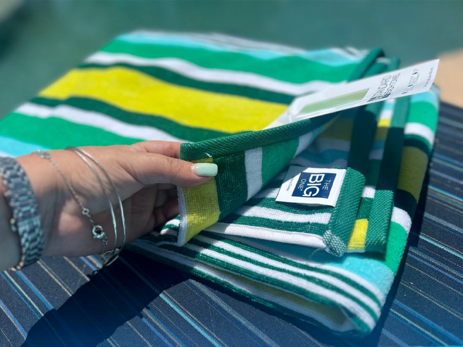 hand lifting up big one towel sitting on chair