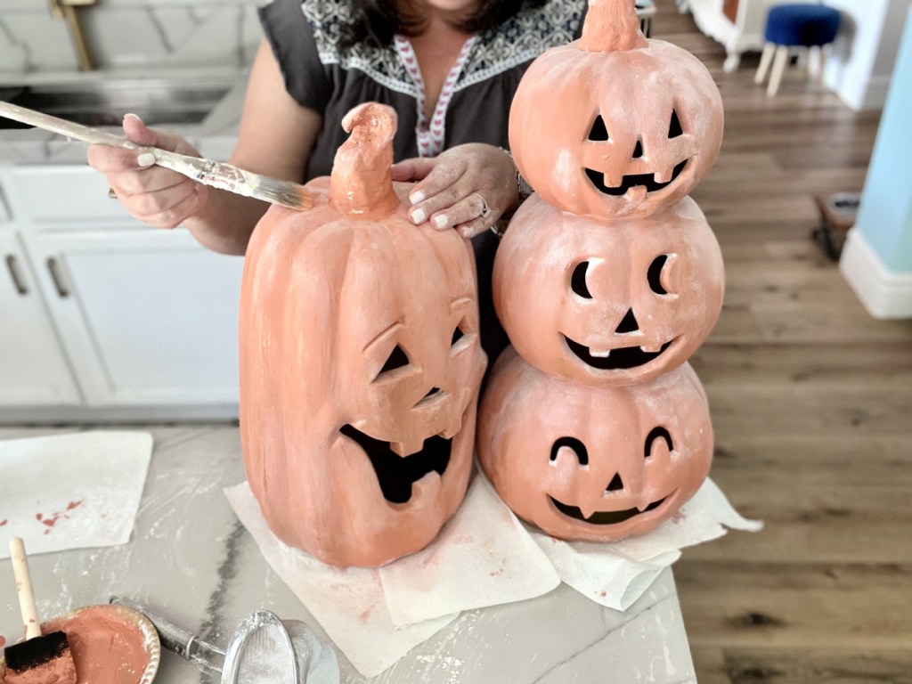 using a dry paint brush to brush off starch on a pumpkin