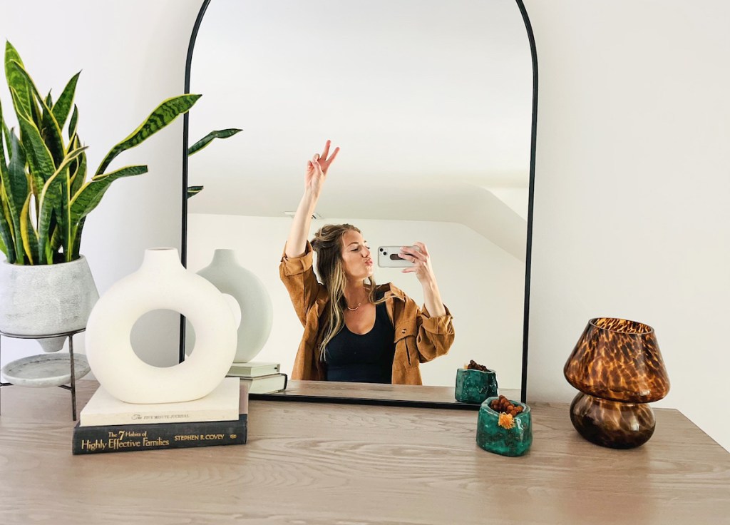 woman taking mirror selfie giving peace sign