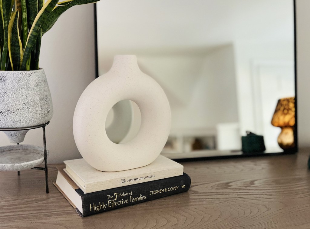white modern vase sitting on top of books