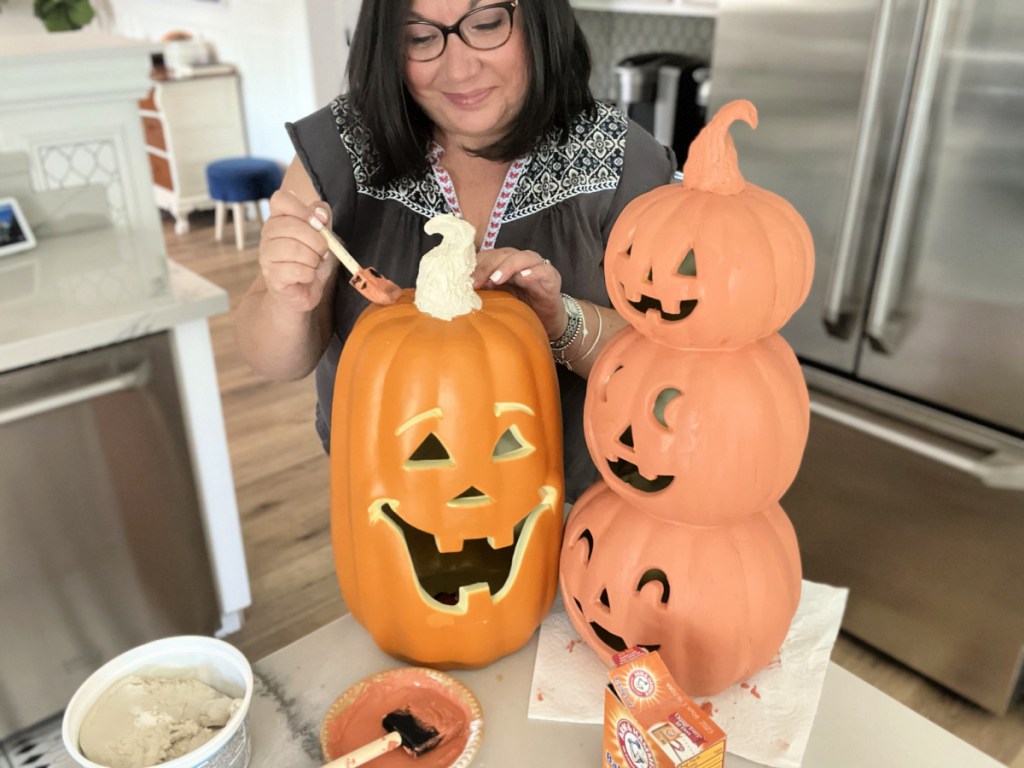 woman painting faux terracotta pumpkins