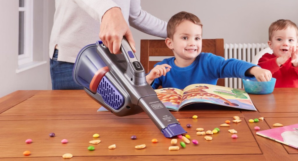 woman using Black and Decker Furbuster Vacuum on the table with children and snacks around