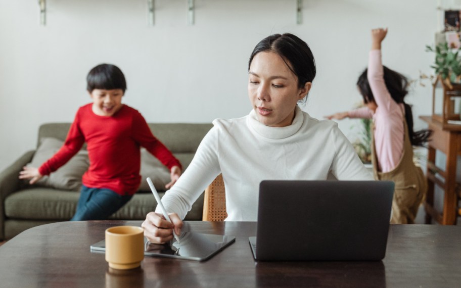 women applying for student loan grants and student loan forgiveness programs while working with her children in the background