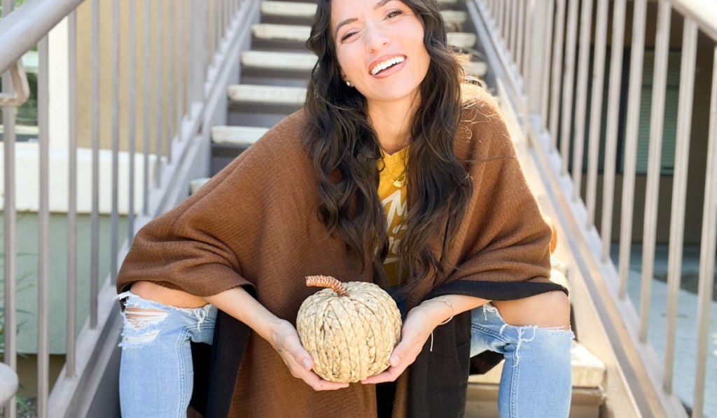 woman holding pumpkin on stairs wearing kohls ruana