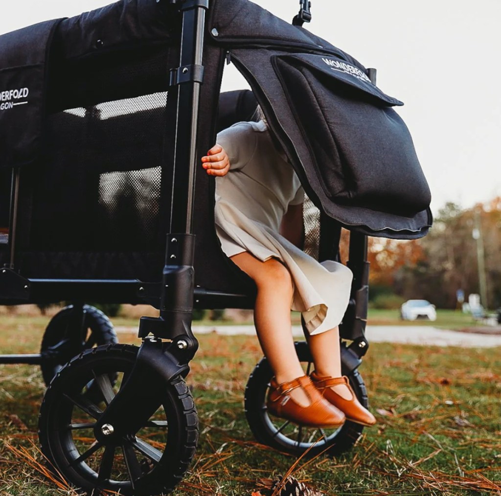 toddler climbing out of wonderfold wagon in grass