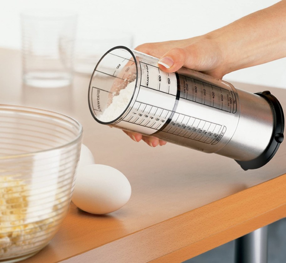 Person using an Adjust-A-Cup Measuring cup which is one of our favorite cool kitchen gadgets
