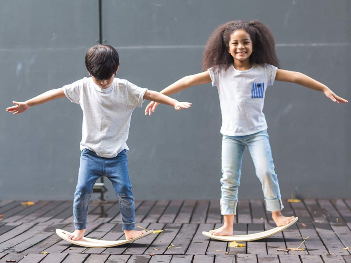 two kids on Amazon Basics Balance Boards on a brick surface
