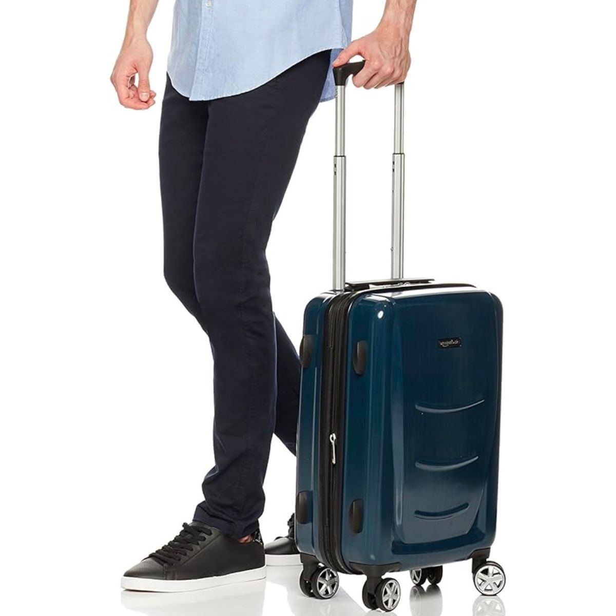 a man pulling a Amazon Basics Hard Shell Carry On Spinner Suitcase 22 inch in navy blue 