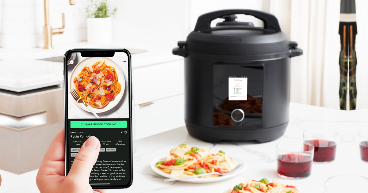 holding up recipe on phone in front of pressure cooker