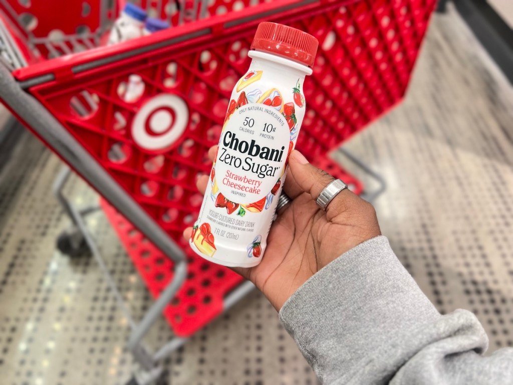 Hand holding a Chobani Zero Sugar Yogurt Drink by a Target cart
